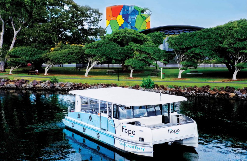 a blue and white Hopo Ferry on the water with green trees in the background