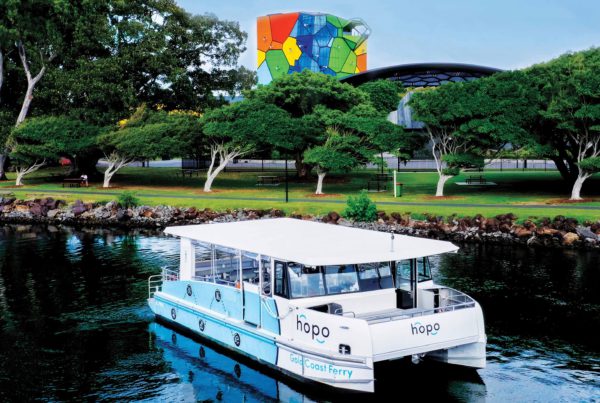 a blue and white Hopo Ferry on the water with green trees in the background