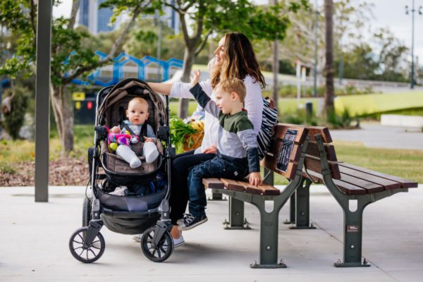 Woman with son sitting on sit with baby in pram