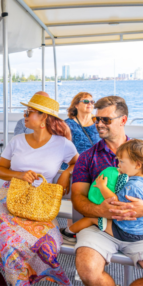 Woman in white shirt next to her male partner in a purple shirt holding their child in a blue shirt, sitting inside the Hopo Ferry.