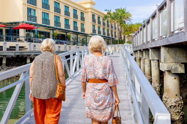 Two older ladies wearing orange walking on wharf