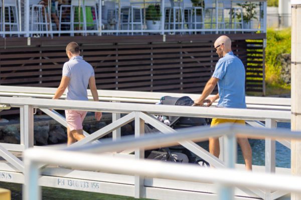 Two husbands pushing a pram up a boat wharf